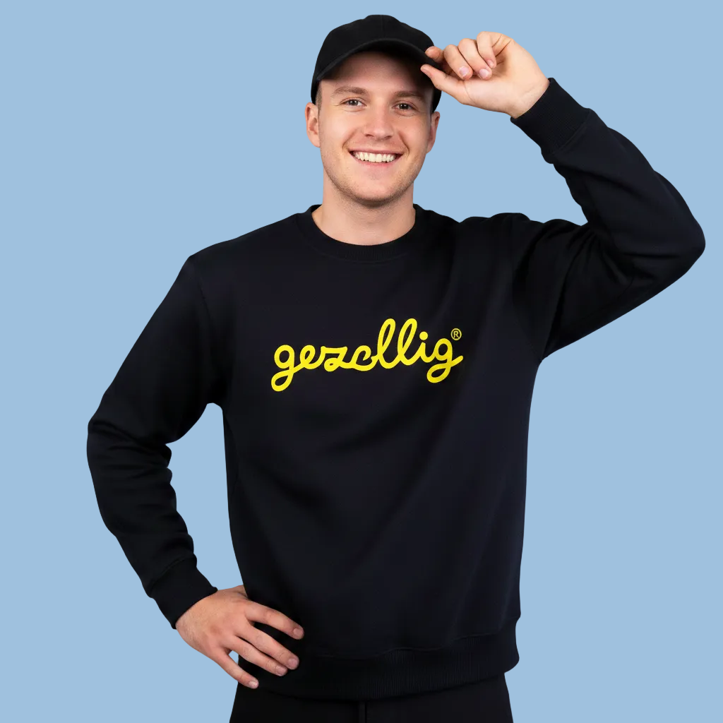 Guy wearing a black Gezellig sweatshirt with yellow logo 