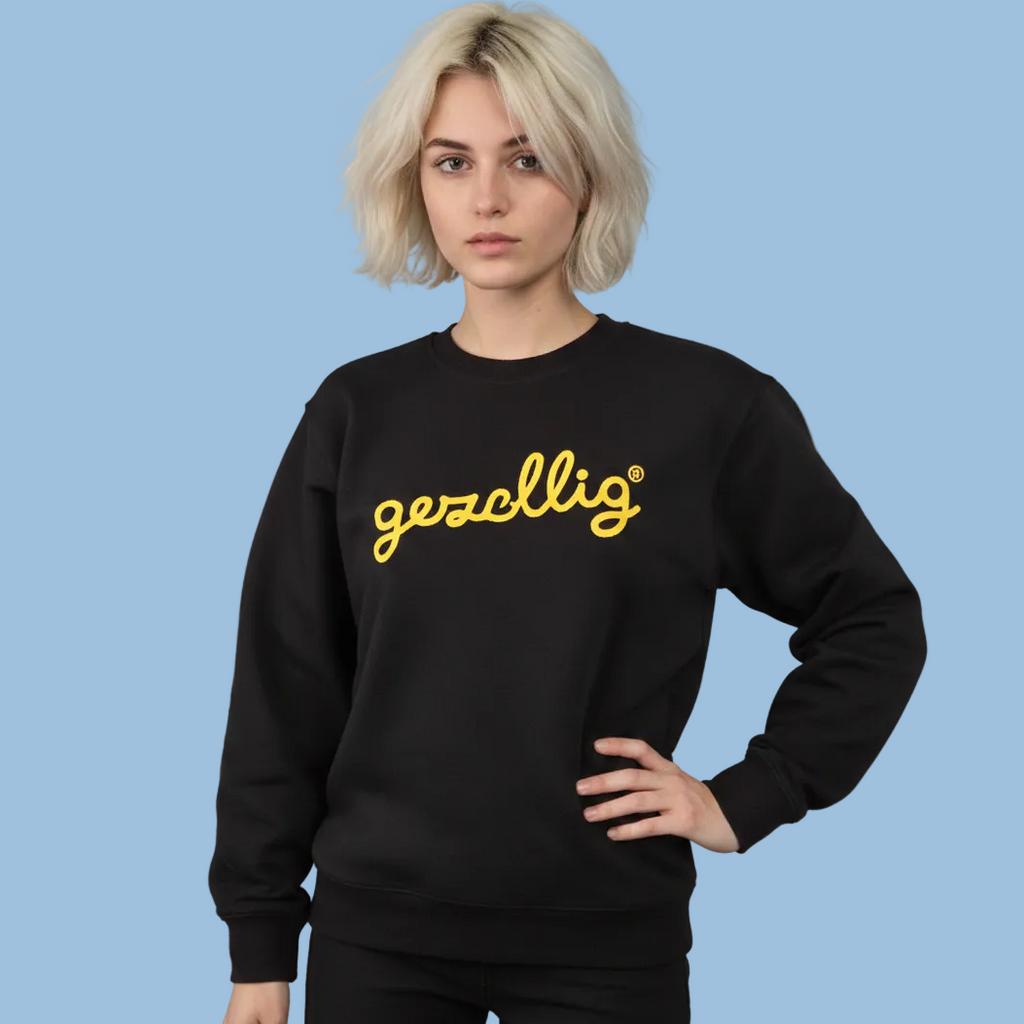 Girl wearing a Gezellig black sweatshirt with yellow logo against a blue background