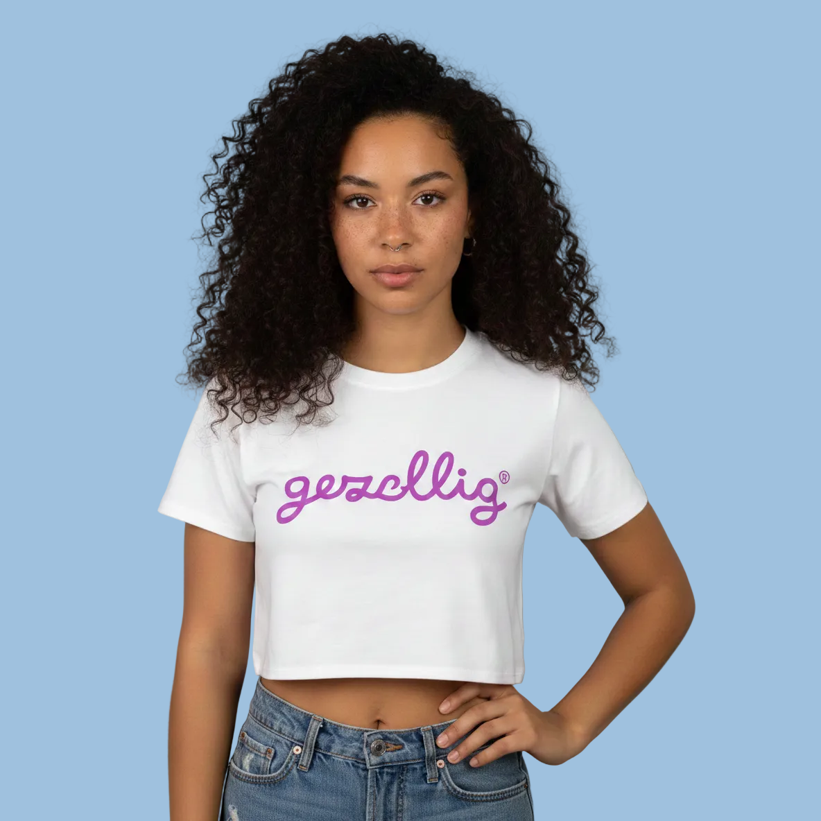 Girl wearing a white Gezellig crop top with fuchsia logo against a light blue background