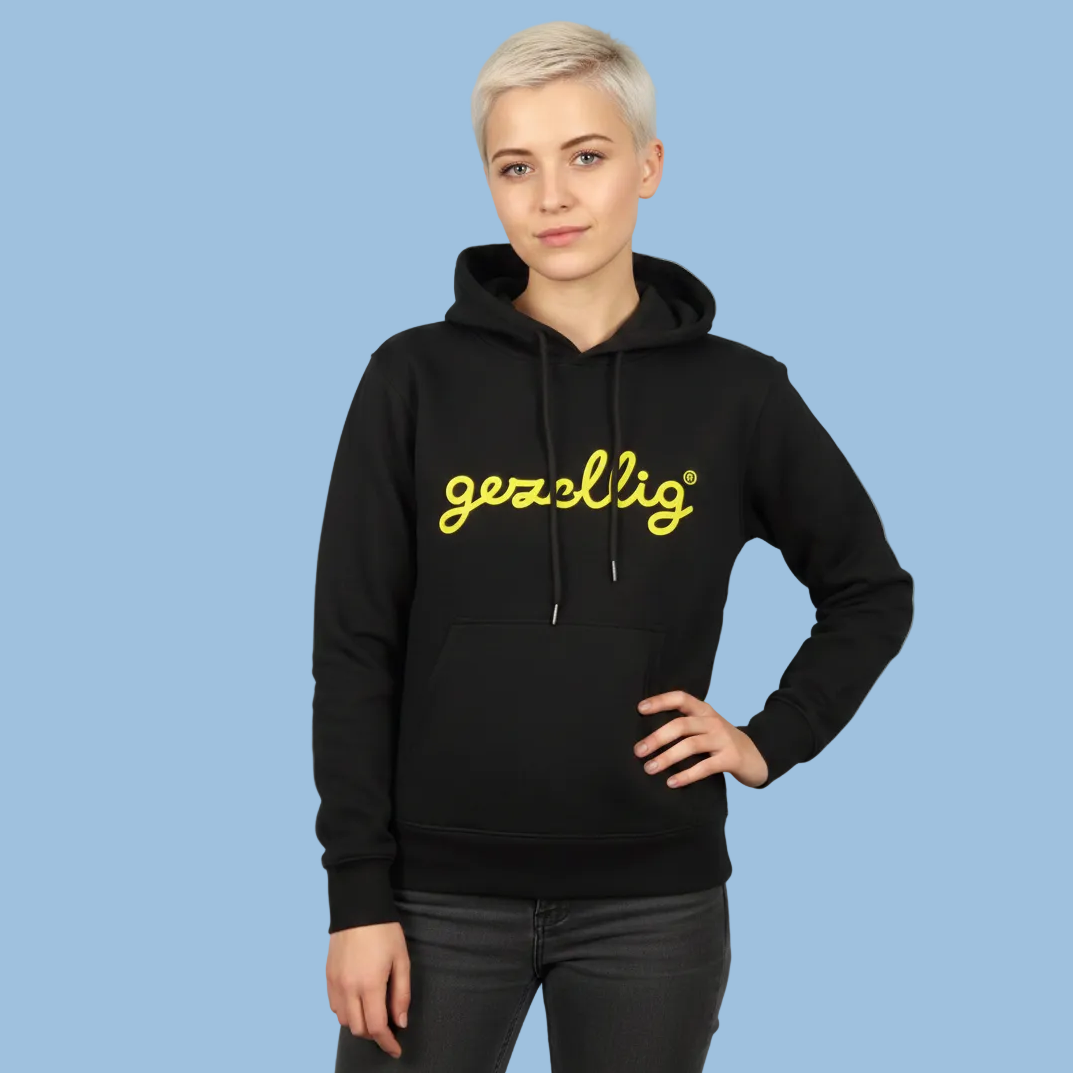 Girl wearing a gezellige black hoodie with yellow Gezellig logo on a light blue background