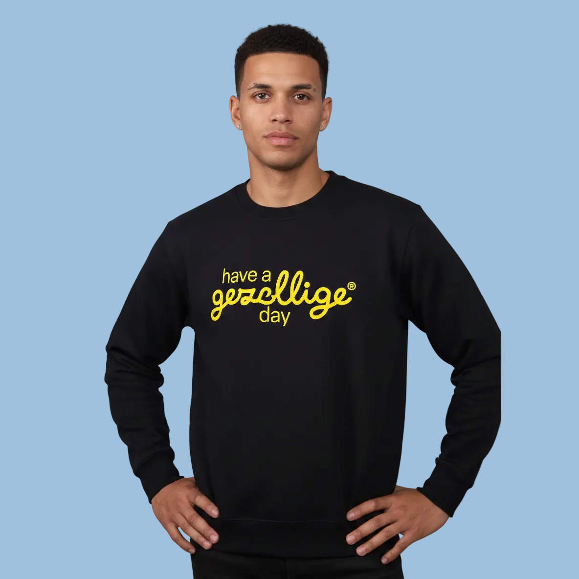 Man wearing a black sweater with yellow text Have a Gezellige Day against a light blue background