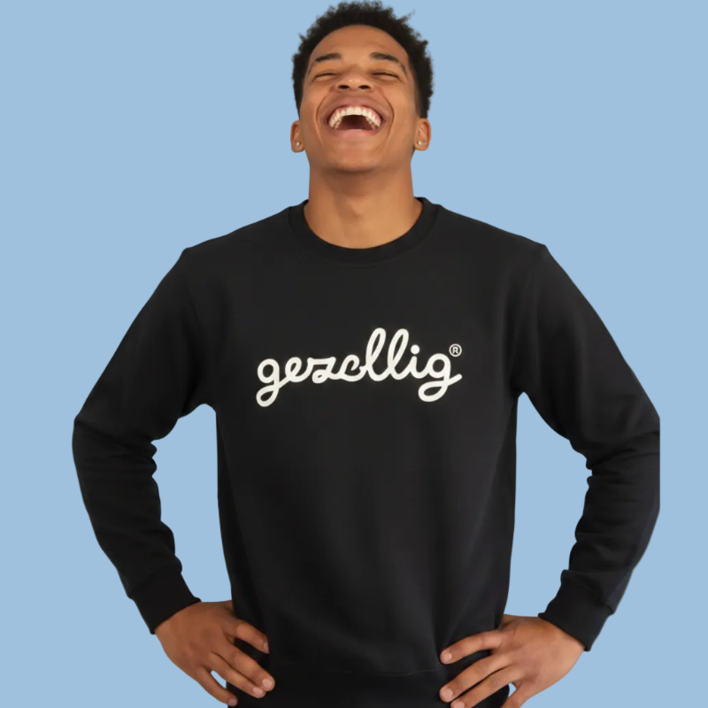 Person wearing a black sweatshirt with 'gezellig' text on a light blue background