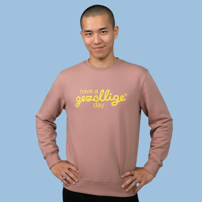 Person wearing a pink sweatshirt with yellow text Have  a Gezellige Day against a  blue background